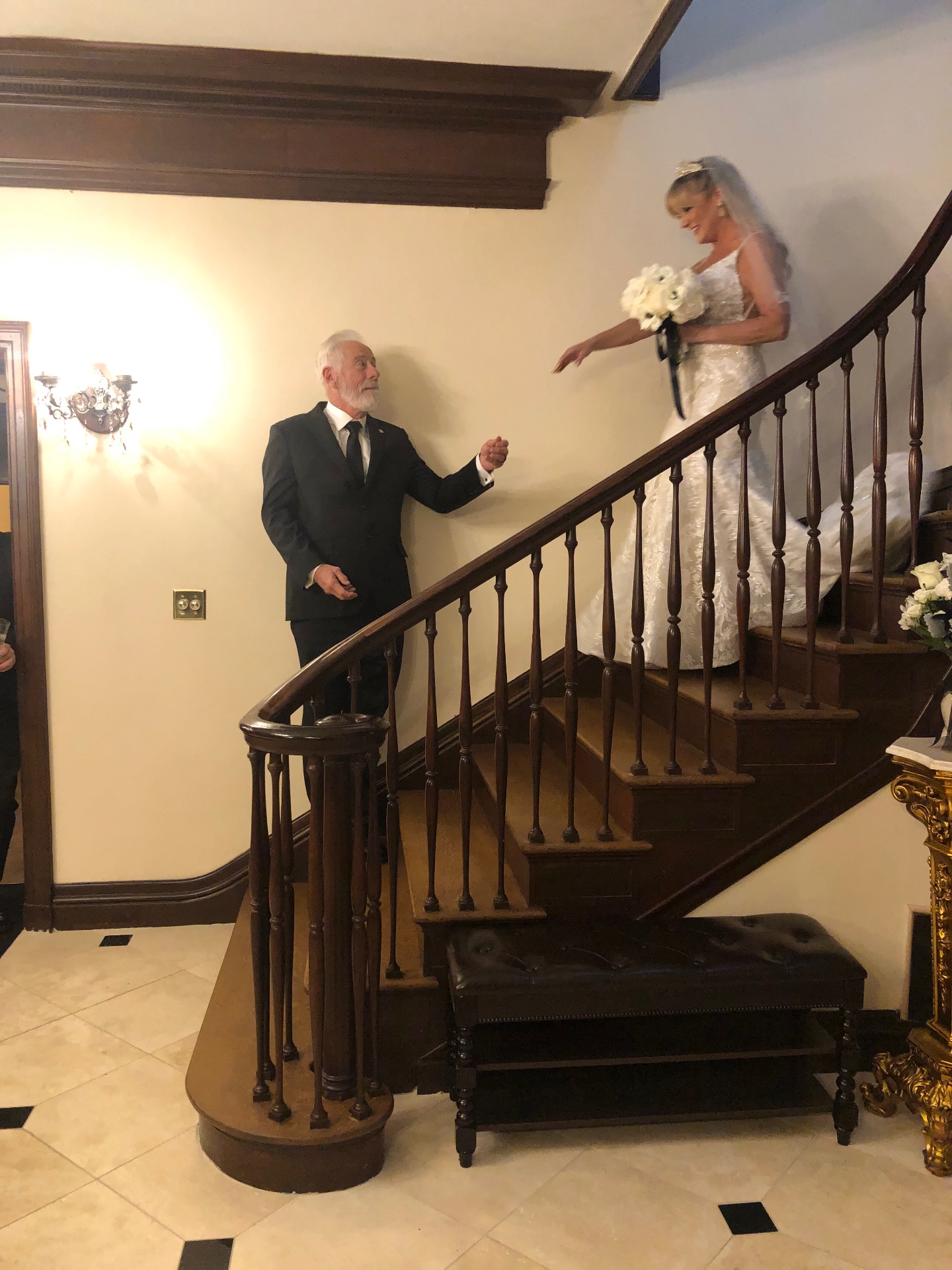 Bride descending the mahogany staircase with her father