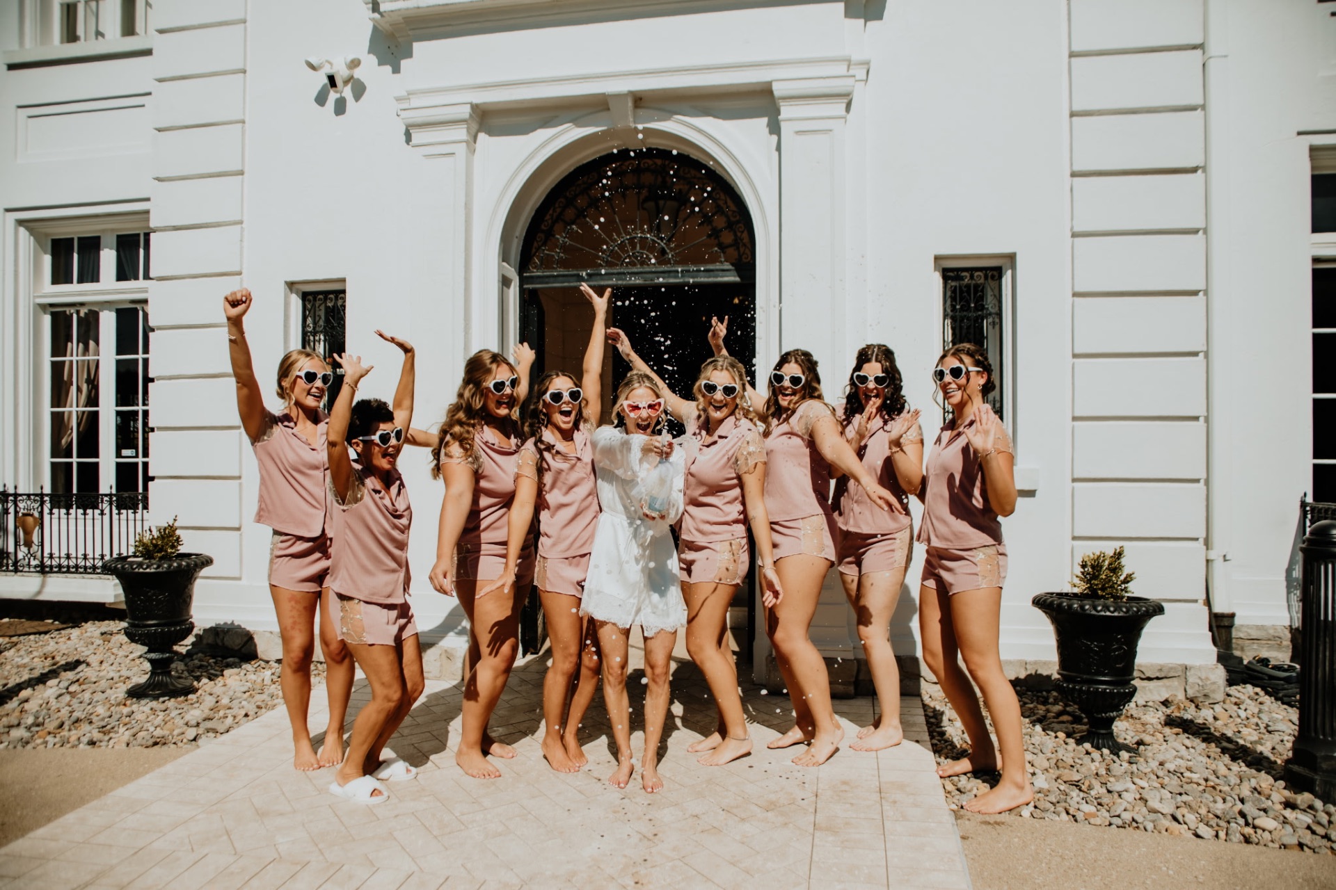 Bride and bridesmaids celebrating with champagne outside the mansion